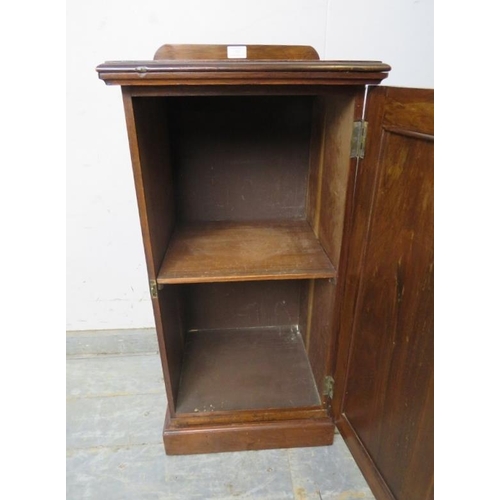 760 - An Edwardian mahogany bedside cabinet, the panelled door opening onto a loose shelf, on a plinth bas... 