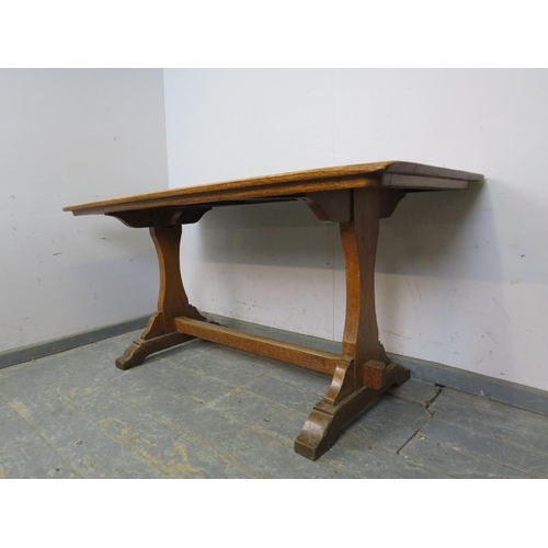 778 - A vintage medium oak trestle end dining table, the planked top on shaped trestle supports with a cha... 