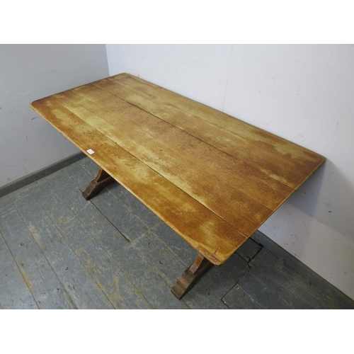 778 - A vintage medium oak trestle end dining table, the planked top on shaped trestle supports with a cha... 