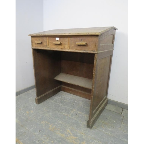 797 - An early 20th century oak schoolmaster’s desk/lectern, having a sloped top above three short drawers... 