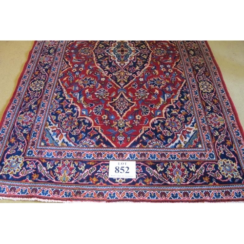 856 - A central Persian Kashan rug.  Central motif of blue, surrounded by a red ground and white borders. ... 