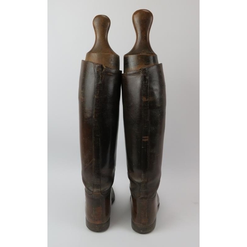 21 - An antique pair of brown leather riding boots with wooden boot trees included. Boots by Huntley & So... 