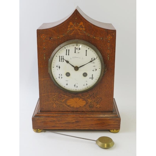 276 - An inlaid oak Edwardian mantel clock by J.W. Benson with striking movement. Pendulum included, no ke... 