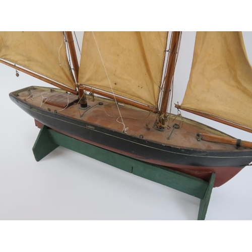 28 - A vintage hand painted wood model of a sailing boat. Displayed on a wooden stand. 56 cm total height... 