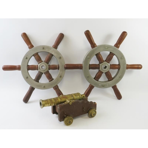 283 - A brass scratch made model of a ships cannon, 24.5cm long and two ships wheels, diameter 42cm. (3)
C... 