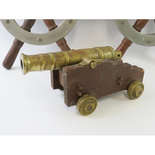 283 - A brass scratch made model of a ships cannon, 24.5cm long and two ships wheels, diameter 42cm. (3)
C... 