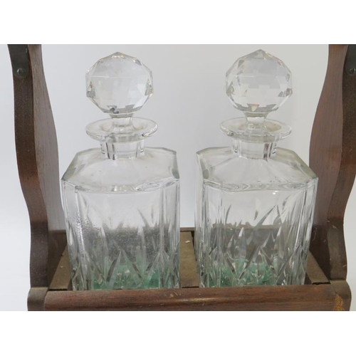 292 - A 20th century oak tantalus housing two cut crystal spirit decanters. Height 32cm. Width 32cm.
Condi... 