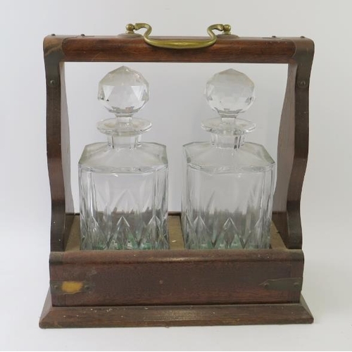 292 - A 20th century oak tantalus housing two cut crystal spirit decanters. Height 32cm. Width 32cm.
Condi... 