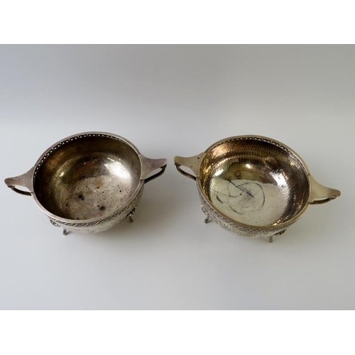 383 - A pair of 1930s planished silver footed bowls with green man mask feet, reticulated rims and twin ha... 