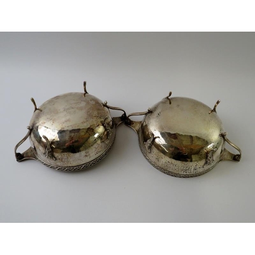 383 - A pair of 1930s planished silver footed bowls with green man mask feet, reticulated rims and twin ha... 