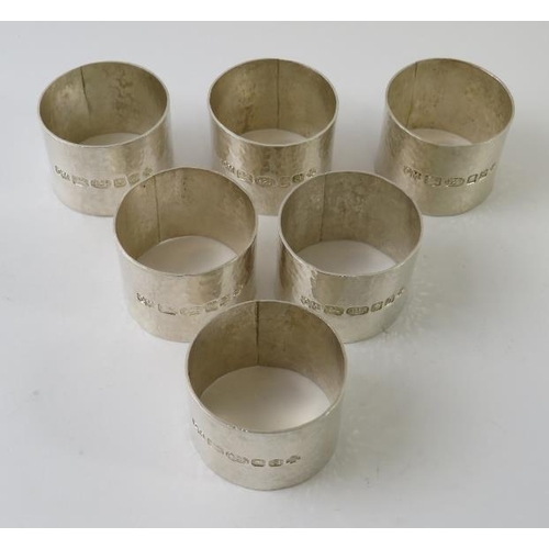 411 - A set of six modernist planished silver napkin rings bearing 2000 Millennium London hallmarks, maker... 