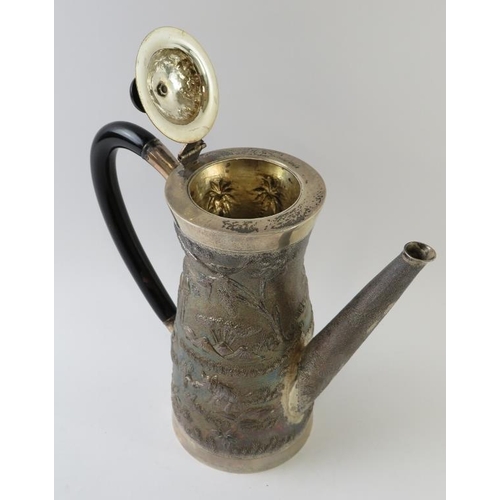 421 - A Far Eastern white metal coffee pot with embossed village scene decoration and ebonised handle and ... 