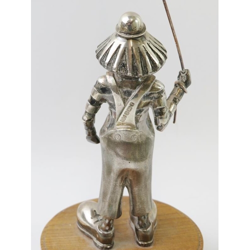 447 - An amusing silver clown figure with kite, mounted on an oak plinth, by Eaton & Jones of Tenterden. H... 