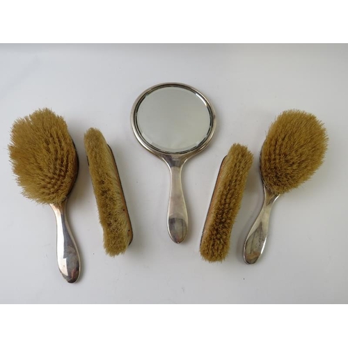 450 - A five piece 1920s silver and tortoiseshell vanity set comprising of hand mirror, two hair brushes a... 