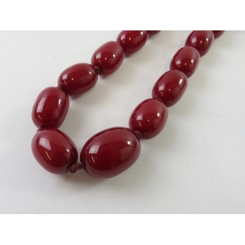 463 - A graduated strand of resin red amber beads 105cm long; and a pair of drop screw-back earrings, 138g... 