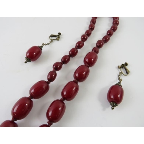 463 - A graduated strand of resin red amber beads 105cm long; and a pair of drop screw-back earrings, 138g... 