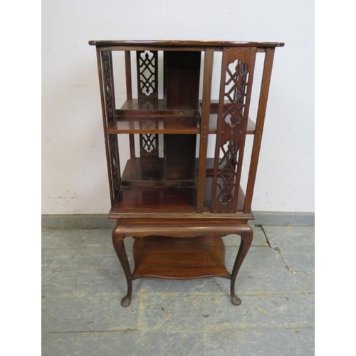 718 - An Edwardian mahogany revolving book table, the shaped top above pierced fretwork side panels and op... 