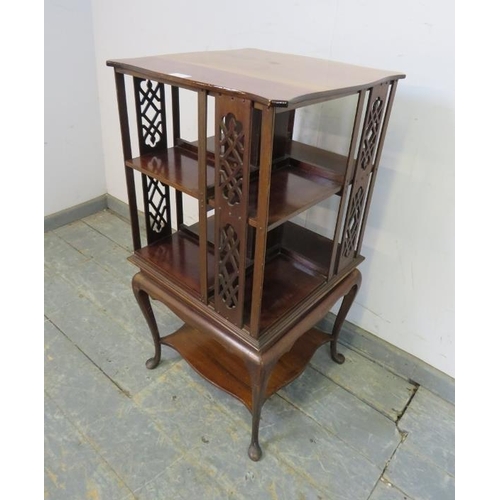 718 - An Edwardian mahogany revolving book table, the shaped top above pierced fretwork side panels and op... 