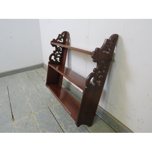 734 - A Victorian mahogany wall-hanging shelf, of three open shelves with chamfered edges and carved and p... 