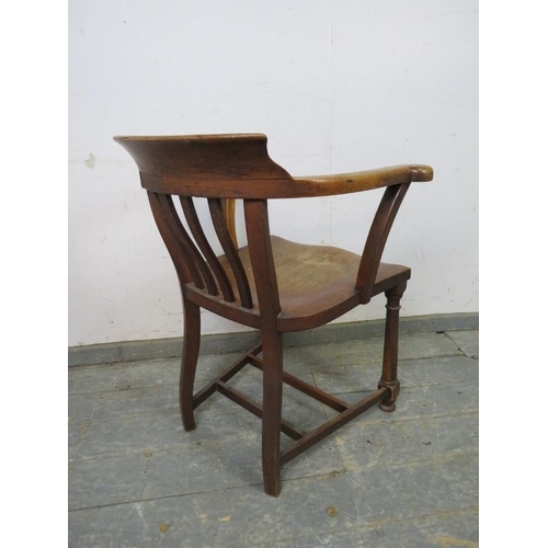 748 - A turn of the century oak captain’s chair, the backrest with antique claret leather with brass studs... 