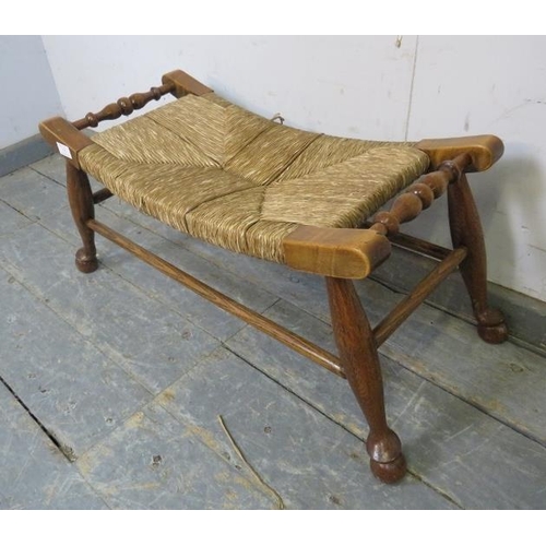 752 - An antique Arts & Crafts Period oak footstool, the curved rush seat on turned supports joined with s... 