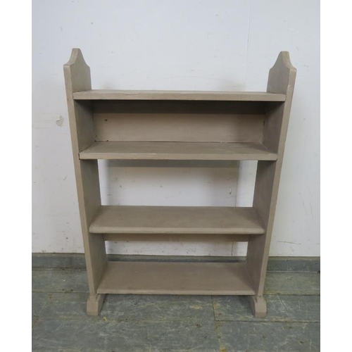 757 - An antique pine open bookcase of four shelves, painted grey, the shaped sides with relief carved Kni... 