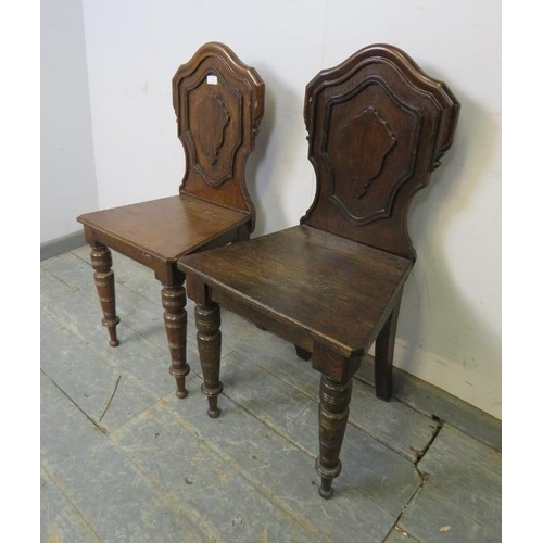 763 - A pair of Victorian oak hall chairs, the shaped backs with relief carved decoration, on tapered turn... 