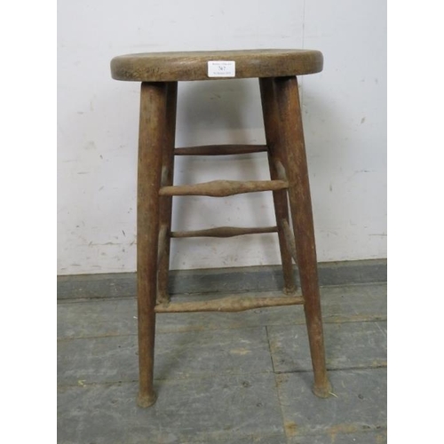 767 - An antique elm artist’s stool, the dished oval top on tapered supports with pad feet, joined by doub... 