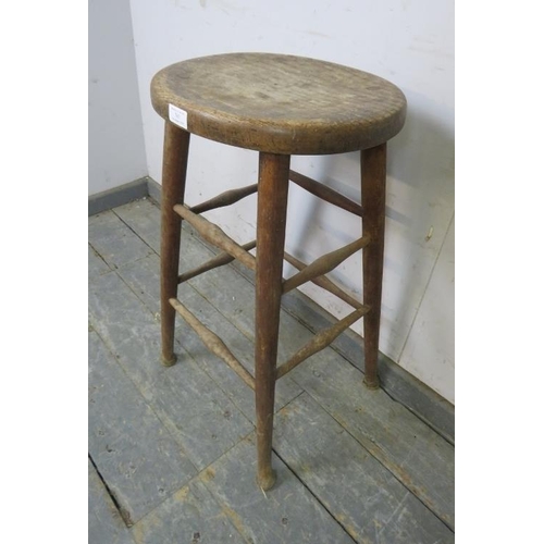 767 - An antique elm artist’s stool, the dished oval top on tapered supports with pad feet, joined by doub... 