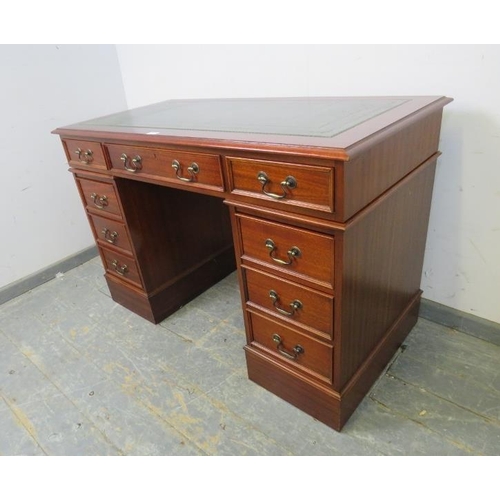 768 - An antique style reproduction mahogany pedestal desk, the top with inset green leather surface, hous... 