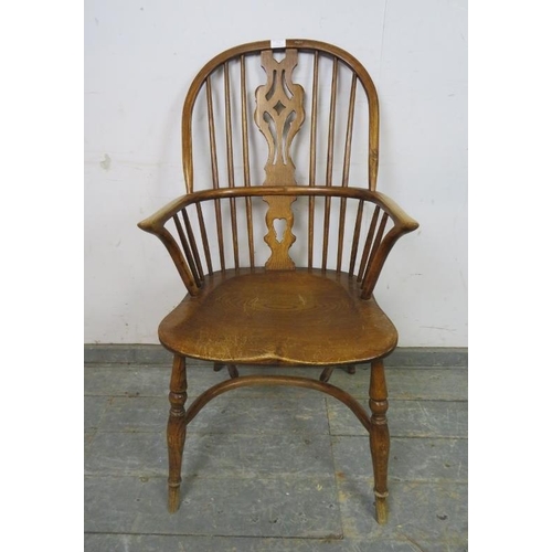 773 - A vintage elm hoop-back Windsor chair in the 19th century style, with shaped and pierced splat, on t... 