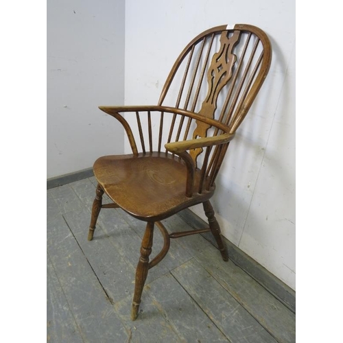 773 - A vintage elm hoop-back Windsor chair in the 19th century style, with shaped and pierced splat, on t... 