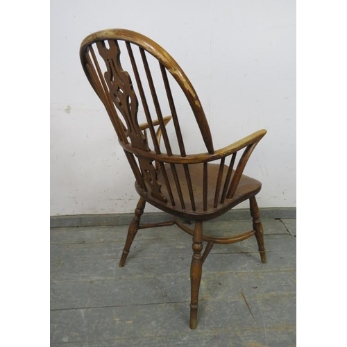 773 - A vintage elm hoop-back Windsor chair in the 19th century style, with shaped and pierced splat, on t... 