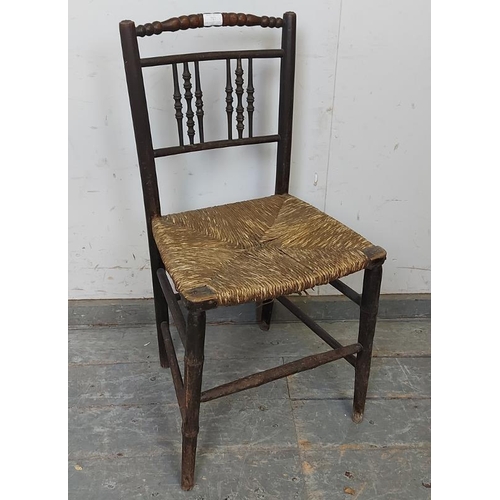 801 - A 19th century ebonised ‘Sussex’ chair, the backrest with turned spindles above a rush seat, on faux... 