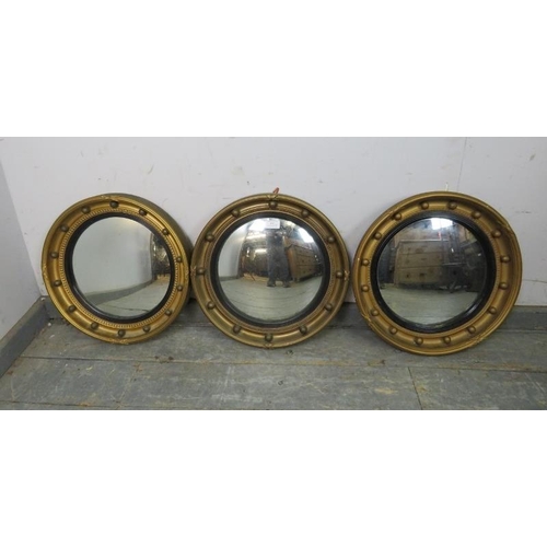 813 - A trio of vintage convex butler’s mirrors, having ebonised reeded borders and gilt surrounds with ap... 