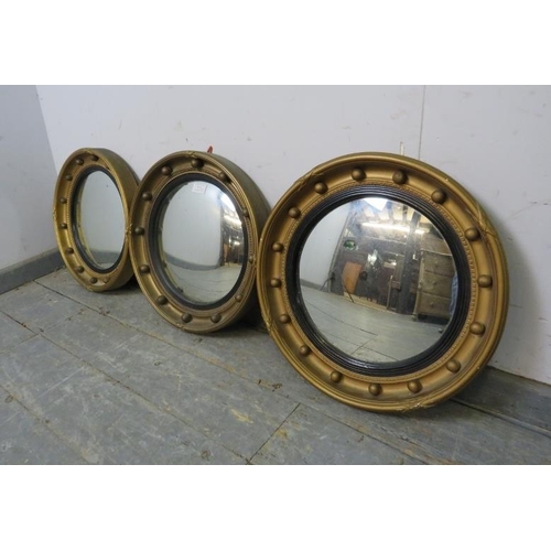 813 - A trio of vintage convex butler’s mirrors, having ebonised reeded borders and gilt surrounds with ap... 