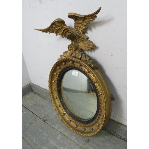 814 - An antique convex mirror in the Regency taste, the reeded ebonised border within a gilt frame with a... 