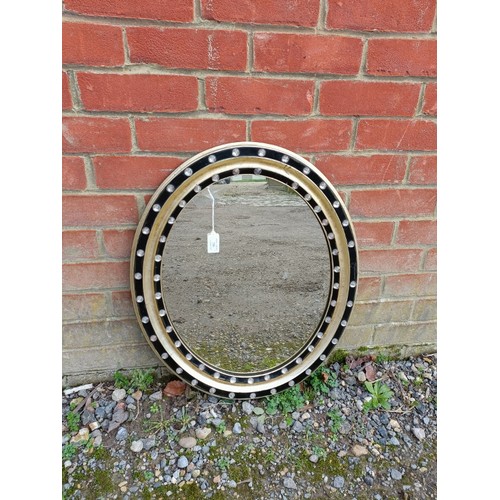 706 - A Regency Period oval wall mirror within a parcel gilt and ebonised surround with applied crystal de... 