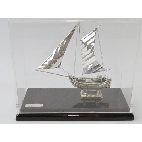 405 - A white metal model sail boat inscribed KAIKI and housed in a clear perspex case. Plaque stamped 'Ha... 