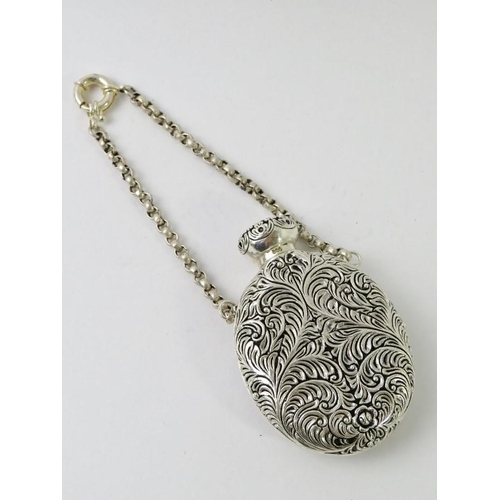 409 - An ornate Continental white metal perfume bottle on chain with foliate decoration and inset cameo st... 