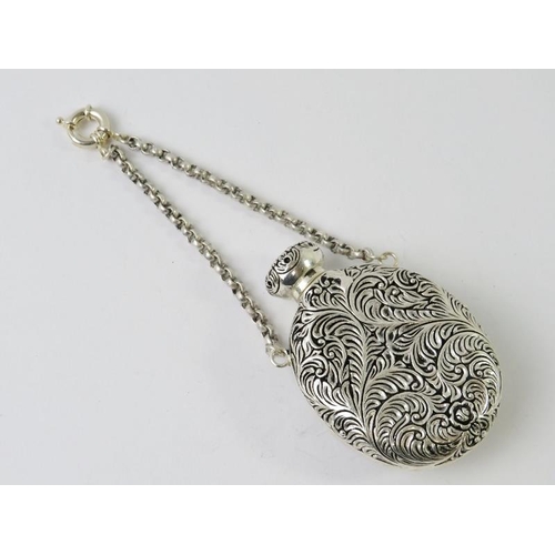 411 - An ornate Continental white metal perfume bottle on chain with foliate decoration and inset cameo st... 