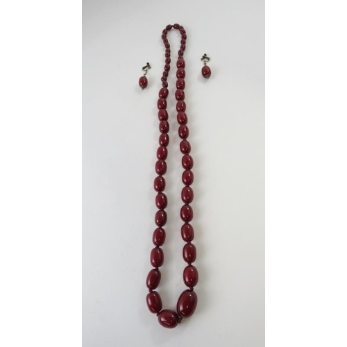 446 - A graduated strand of resin red amber beads 105cm long; and a pair of drop screw-back earrings, 138g... 