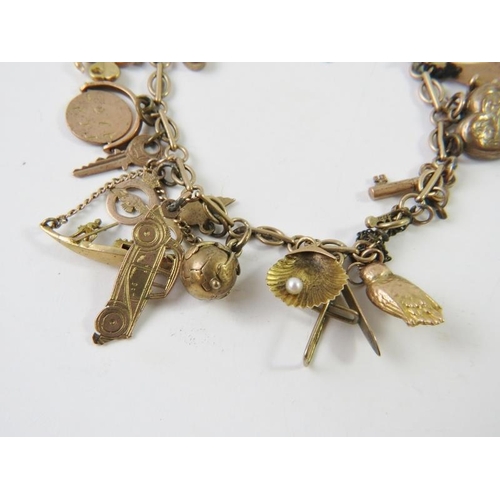 464 - A yellow metal charm bracelet stamped 9c with 20 assorted charms to include an owl, pearl shell, RAF... 