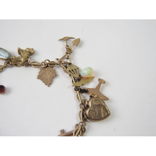 464 - A yellow metal charm bracelet stamped 9c with 20 assorted charms to include an owl, pearl shell, RAF... 