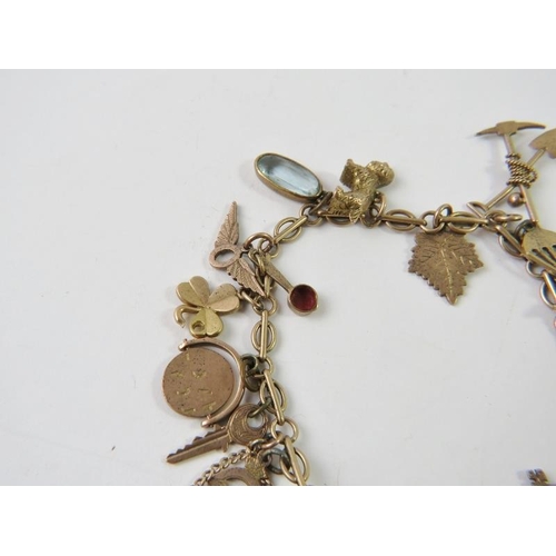 464 - A yellow metal charm bracelet stamped 9c with 20 assorted charms to include an owl, pearl shell, RAF... 