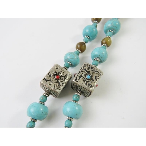 479 - A Tibetan medallion necklace with honey resin, turquoise resin and silvery white metal beads, centra... 