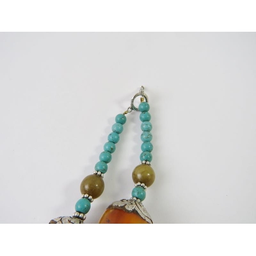 479 - A Tibetan medallion necklace with honey resin, turquoise resin and silvery white metal beads, centra... 