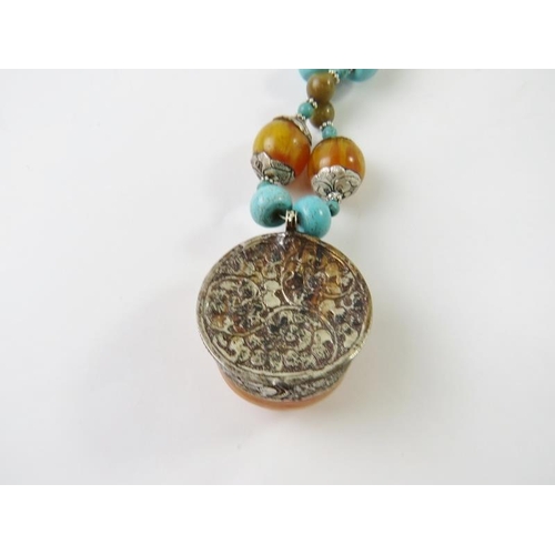 479 - A Tibetan medallion necklace with honey resin, turquoise resin and silvery white metal beads, centra... 