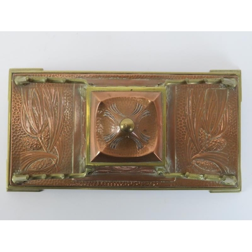 84 - An Arts & Crafts copper and brass desktop inkwell, late 19th/early 20th century. The central inkwell... 