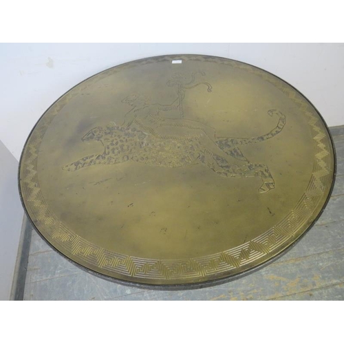 707 - An unusual brass topped folding table, the top with relief decoration depicting a man astride a leop... 